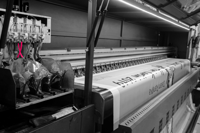 Large-format printed material moving through professional production equipment